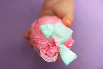 Easter egg in a child's hand. Selective focus. baby find the egg. The egg is wrapped in gift pink paper with mint green ribbon and flower. purple felt background. Creative concept of Easter