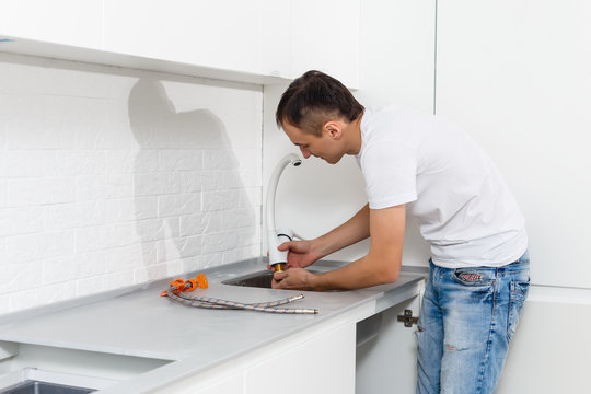 Man fixing sink pipe in kitchen