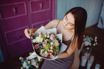 Naklejka premium Young woman holding bouquet of flowers in modern style of rose bush roses, feels scent of smell of spring.