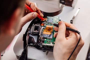 Close up hands of a service worker repairing digital camera.