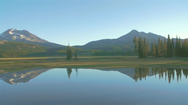 Panning shot of a lake, and some mountains in the background at sunrise
