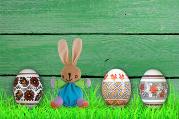 Happy Easter. Colorful easter eggs and rabbit on green grass.