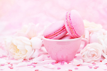 Raspberry and strawberry pink macarons on pastel valentine decor and rose flowers soft background, selective focus, toned