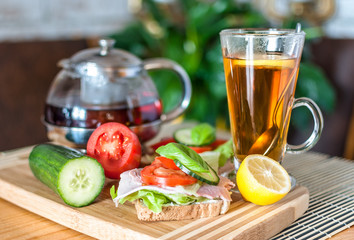 Spring breakfast on the table. Tea, ham sandwich and vegetables. A serving of vitamins for breakfast.