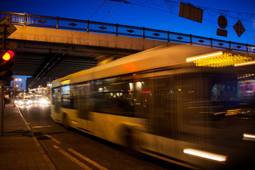 Fototapeta na wymiar The motion of a blurred trolleybus on the street at dusk under the bridge
