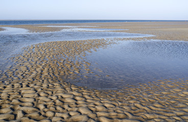 Foehr / Germany: View from the west coast on the island over a the dry fallen seabed and a wide tidal creek in the Frisian Wadden Sea to the island of Sylt in the north