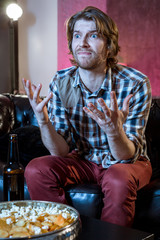 Young supporter man watching football game on television sitting
