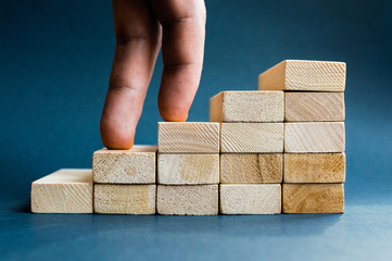 Fingers climbing the stairs made with wooden blocks. Concept of the success, career, goal...
