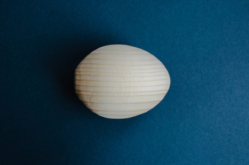 Wooden handcrafted egg ready for art on the blue background. Concept of Easter, joinery, art,...