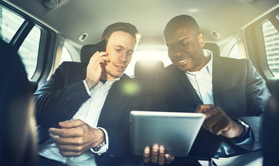 Two colleagues working together in the backseat of a car