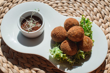 closeup of plate with spanish croquettes served with salad and sauce