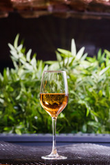 A glass of white wine or apple juice stands on a table in good light with a beautiful green background.