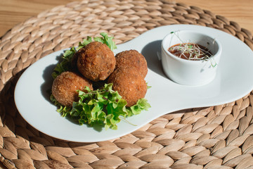 closeup of plate with spanish croquettes served with salad and sauce