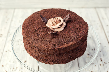 dark chocolate vegan cake with candies and cream on wooden background