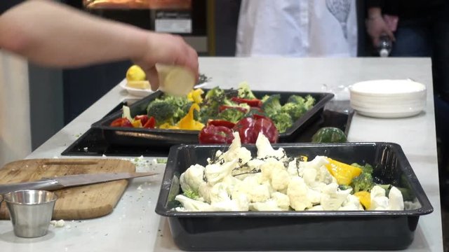 The chef pours the vegetables with sauce. Broccoli, cauliflower and pepper in a tray on the table. HD video