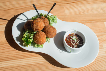 closeup of plate with spanish croquettes served with salad and sauce