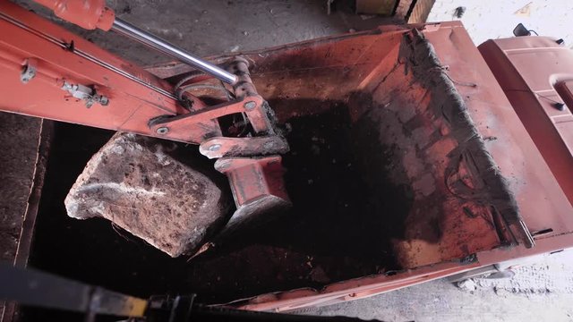 Excavator moving big rocks from a construction site to a truck body.