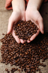 Hands and roasted coffee beans on sackcloth.