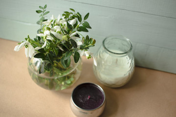 spring white flowers in a glass vase next to candles