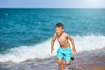 Fototapeta premium European boy is running along the seacost.