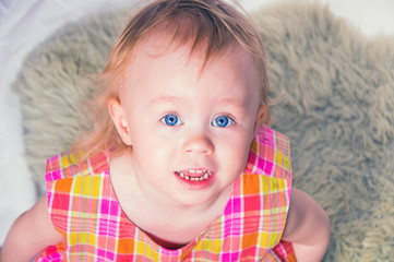 Portret of adorable baby girl with blue eyes and funny hair posing in studio