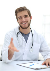 Handsome medical doctor in white coat is offering his hand