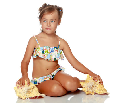Little girl in a swimsuit with a seashell
