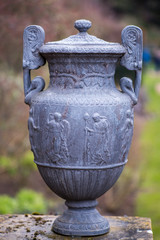 stone Greek urn isolated in English country garden with blurred background