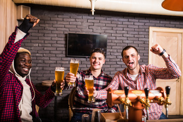 Group of male friends watching football match in pub win shout scream