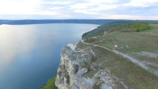 Great sunset on the lake between the mountains. A couple hugging at the edge of the cliff. 4k