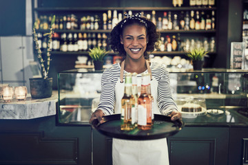 Smiling young African server carrying drinks in a restaurant