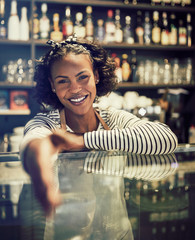 Smiling African entrepreneur shaking hands from behind her cafe