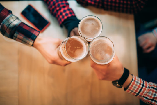 Cheers. Close-up Top View Of Friends Holding Mugs With Beer