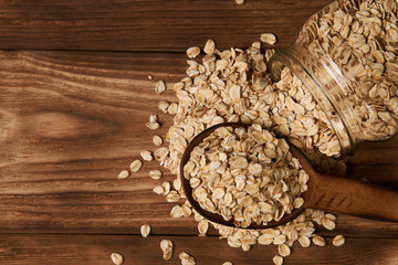 Obraz na płótnie Canvas Dry rolled oat flakes oatmeal on old wooden table background, top view. Healthy vegetarian diet food and agriculture concept