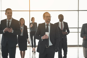 Group of employees standing in business center separately from each other with paper cups in hands