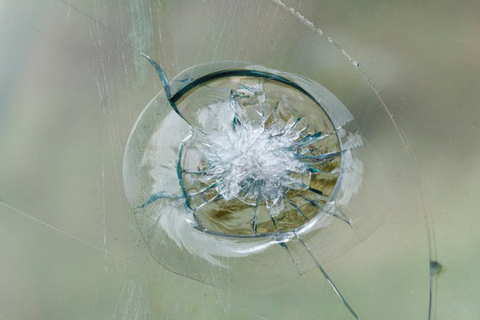 Firearms bullethole on bulletproof glass, cracks background
