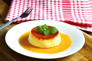 Caramel custard desert on white dish with wooden background