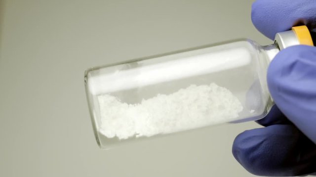 white powder medication inside a glass ampoule. close-up