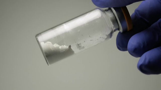 white powder medication inside a glass ampoule. close-up