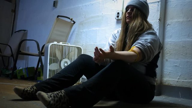 A Woman injects herself with a heroin needle in a trap house ALT