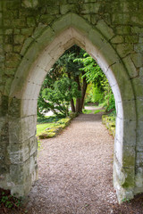 A Path Beyond the Arched Stone Wall in A European Abbey