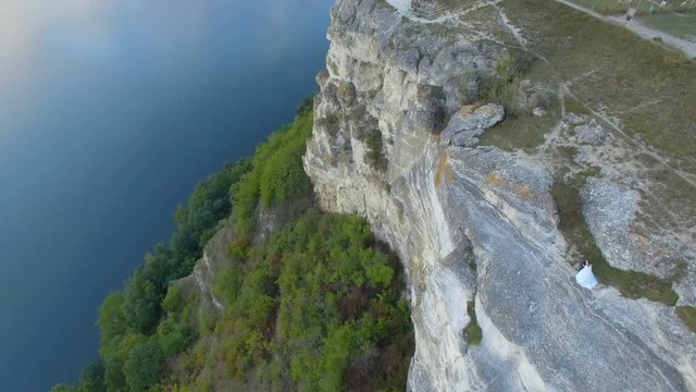 Great sunset on the lake between the mountains. A couple hugging at the edge of the cliff. 4k