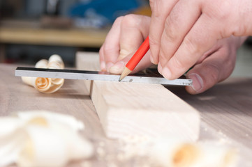 Obraz premium carpenter makes the marking of the wooden part in red pencil
