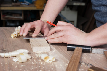 carpenter makes the marking of the wooden part in red pencil .