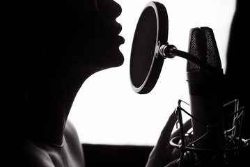 Silhouette of a woman singing a song in a recording studio. Black and White.
