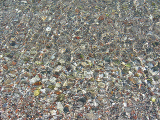 Crystal clean sea water with multicolour pebble on seabed