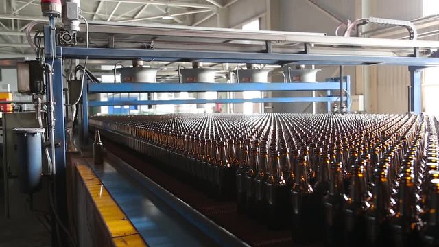 Cooling glass bottles on the glass factory. Production bottles in glass factory. Preparation of beer bottles for bottling and packaging. Rows of beer bottles in the factory. Ambient sound at factory.