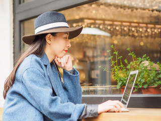 Beautiful young brunette woman working with mobile computer in cafe. Outdoor fashion portrait of glamour young Chinese business stylish lady. Emotions, people, beauty and lifestyle concept.