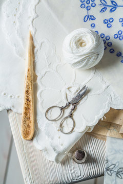 White thread, scissors and homemade embroidered napkins
