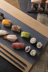 Sushi Set sashimi and sushi rolls served on stone slate